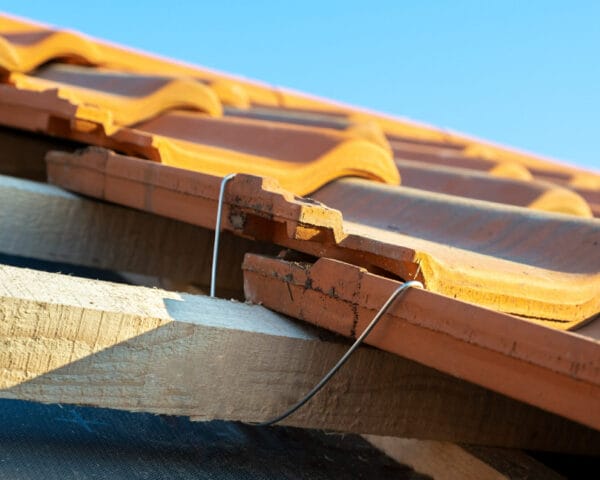 closeup-metal-montage-anchor-installation-yellow-ceramic-roofing-tiles-mounted-wooden-boards-covering-residential-building-roof-construction closeup-metal-montage-anchor-installation-yellow-ceramic-roofing-tiles-mounted-wooden-boards-covering-residential-building-roof-construction