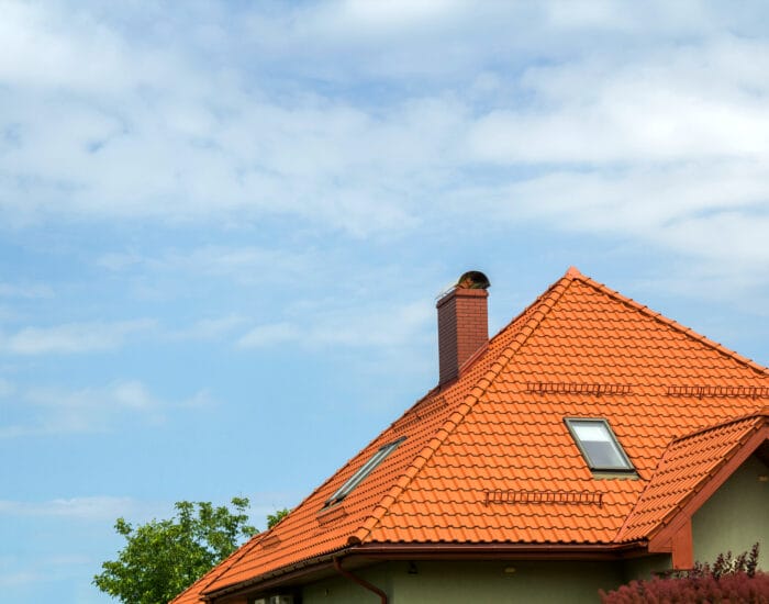 close-up-detail-new-modern-house-top-with-shingled-red-roof-high-chimney-attic-windows-clear-blue-sky